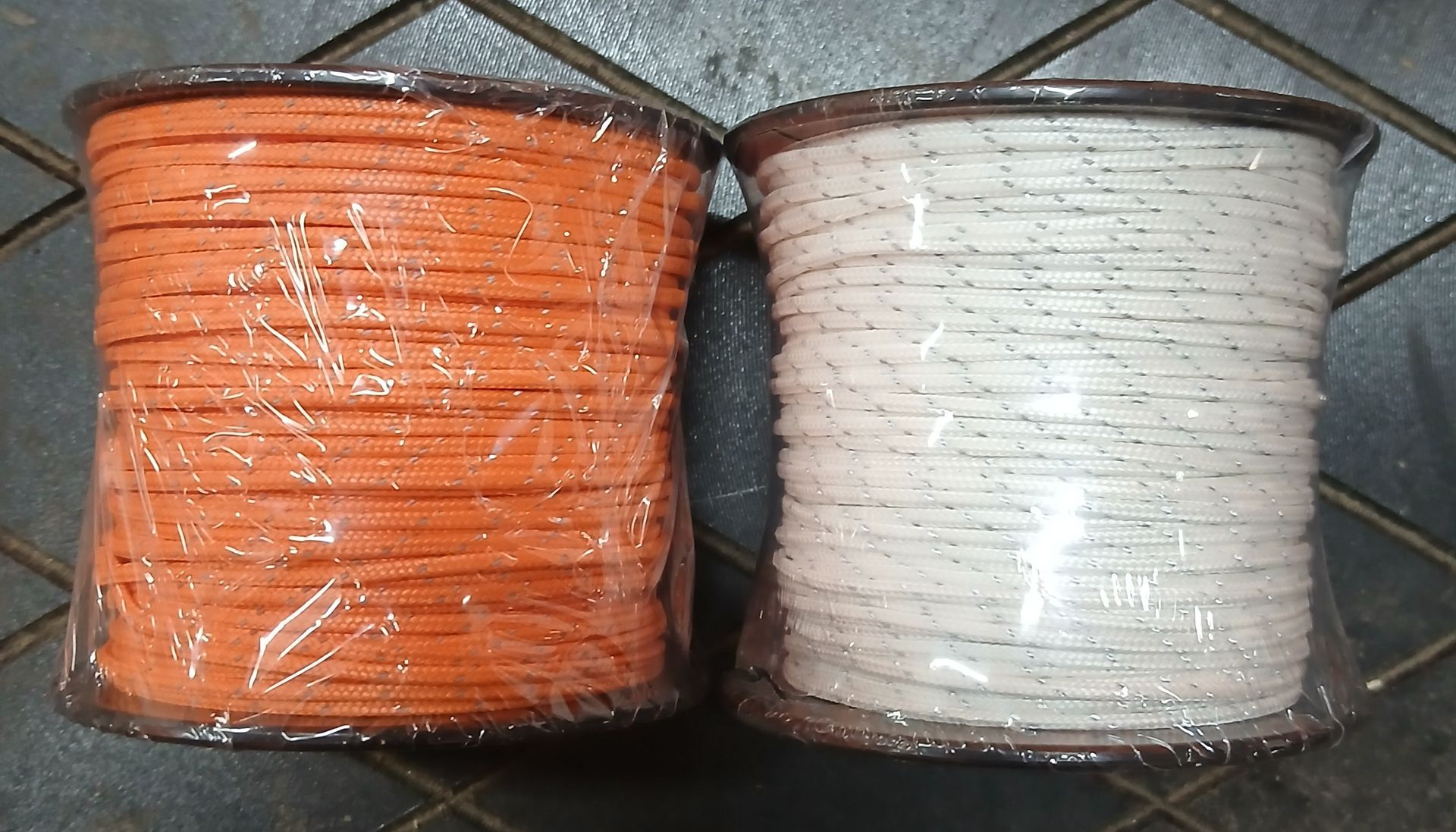 Coiled black and white rope, secured with white plastic straps, resting on a dark surface. Coiled black and white rope, secured with white plastic straps, resting on a dark surface.