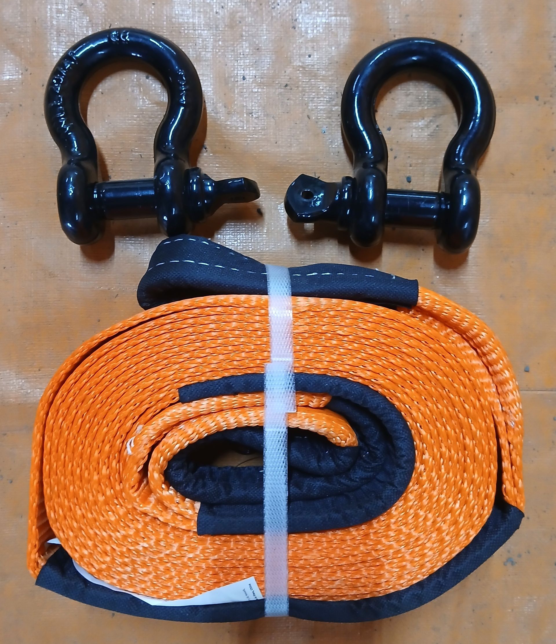 Orange and black tow strap with two black shackles, used for vehicle recovery. Orange and black tow strap with two black shackles, used for vehicle recovery.