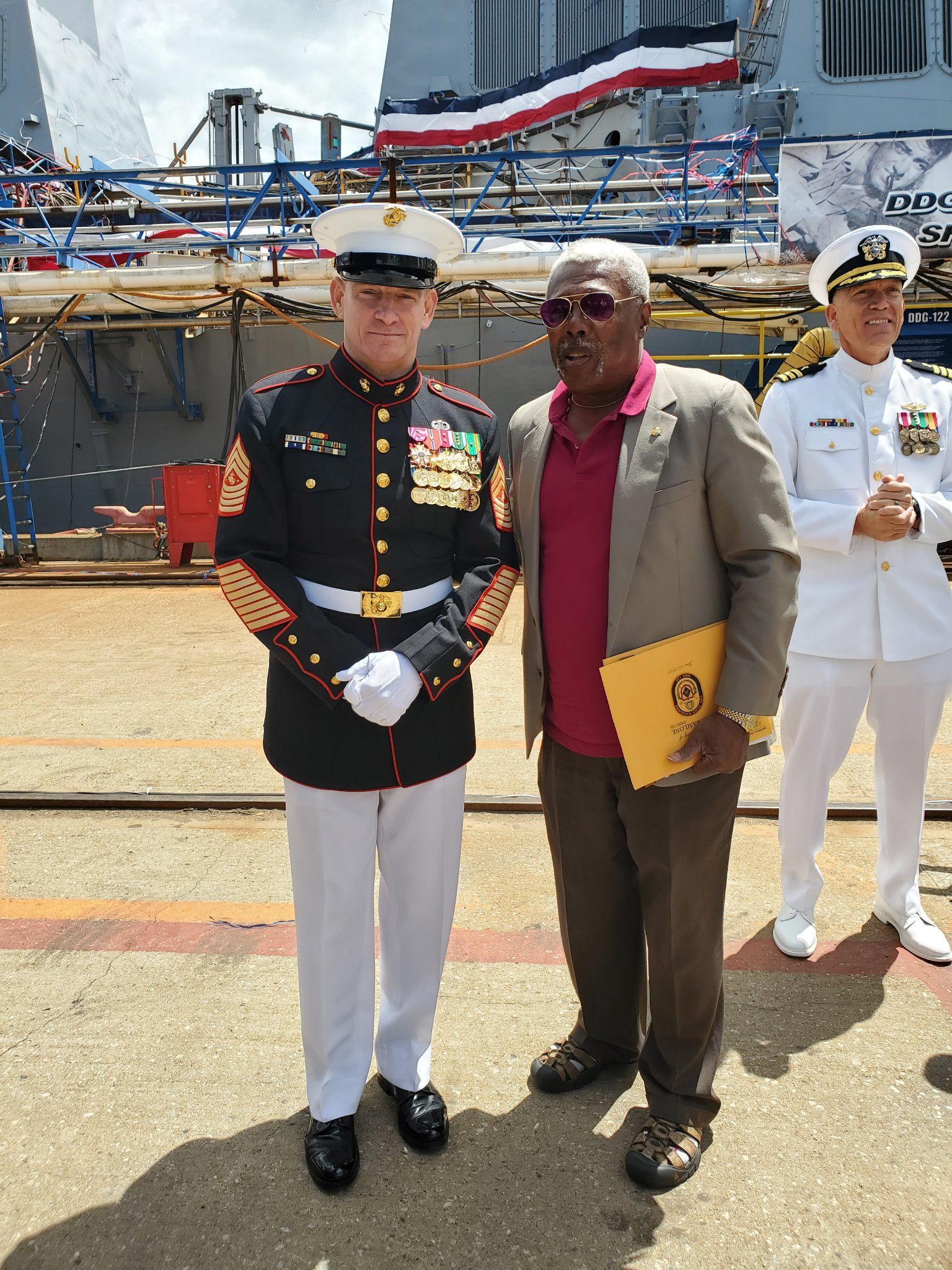 A man in a military uniform is standing next to a man in a suit.