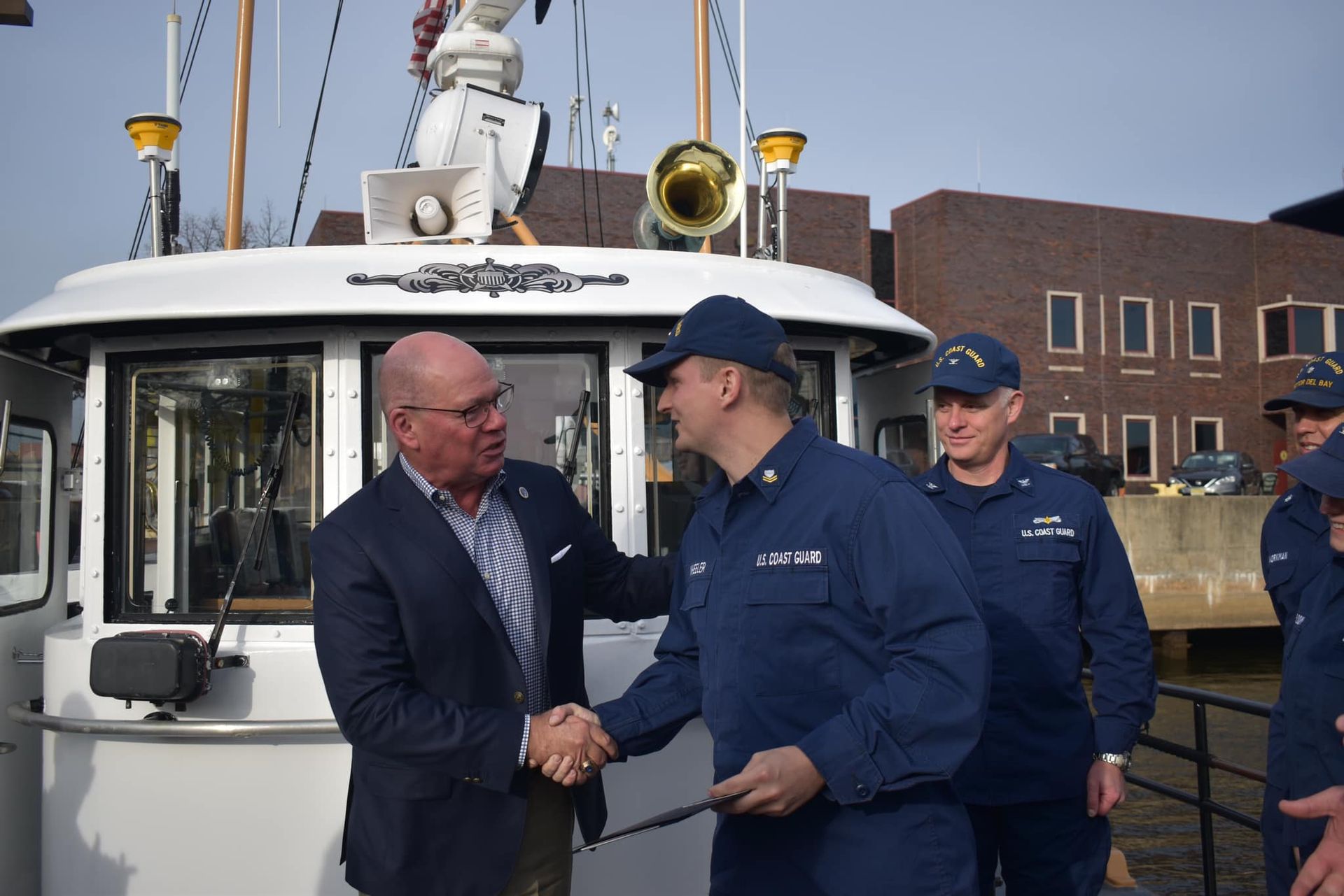 A group of men shaking hands in front of a boat