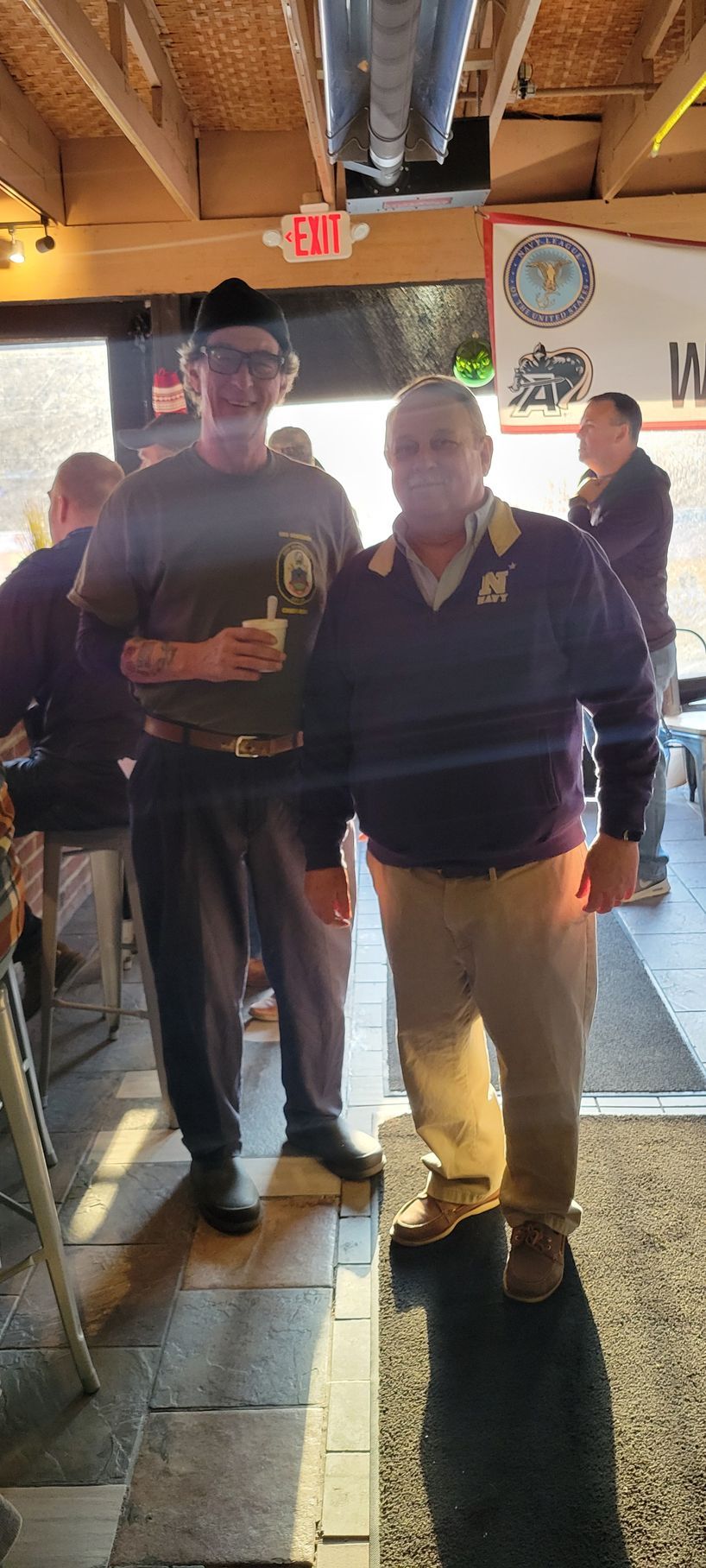 Two men are standing next to each other in a restaurant