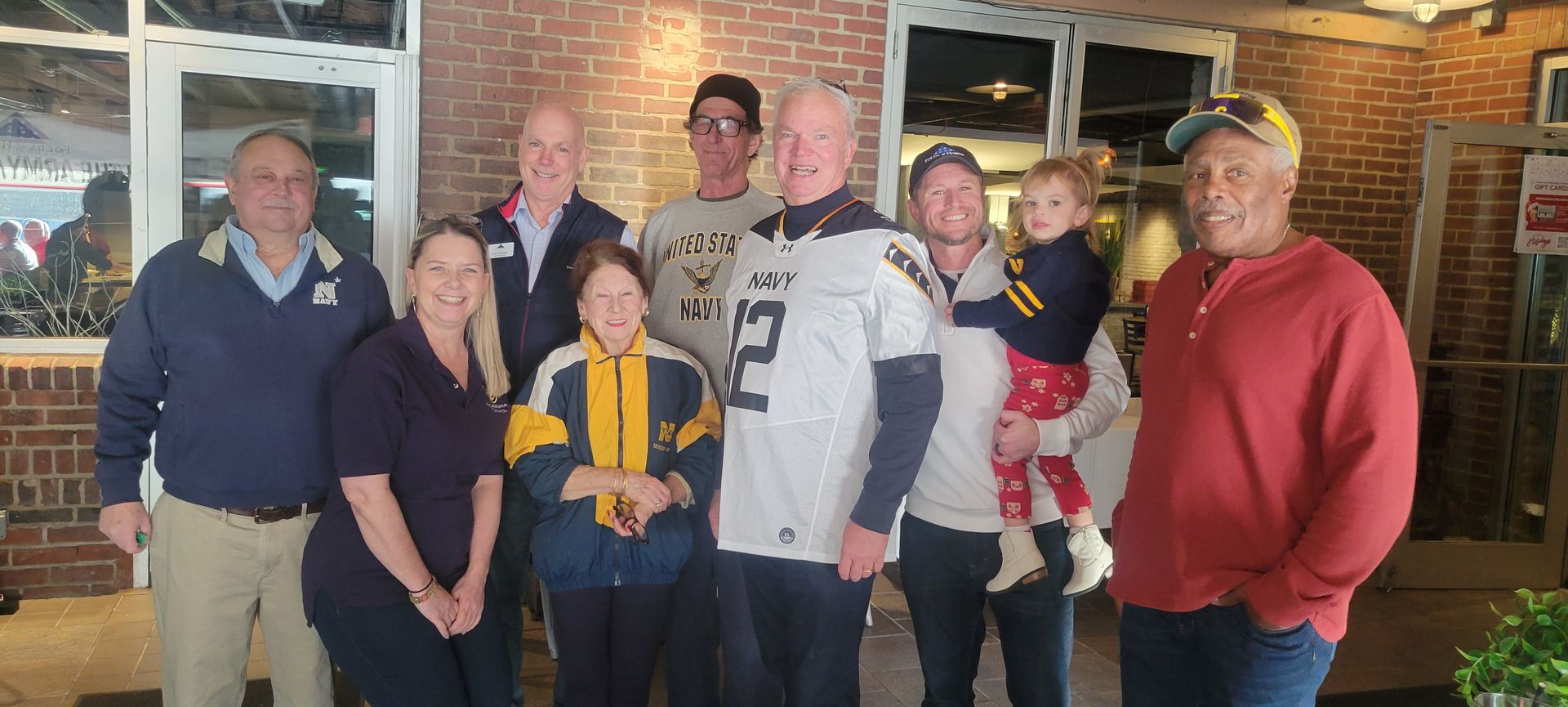 A group of people are posing for a picture in front of a brick building