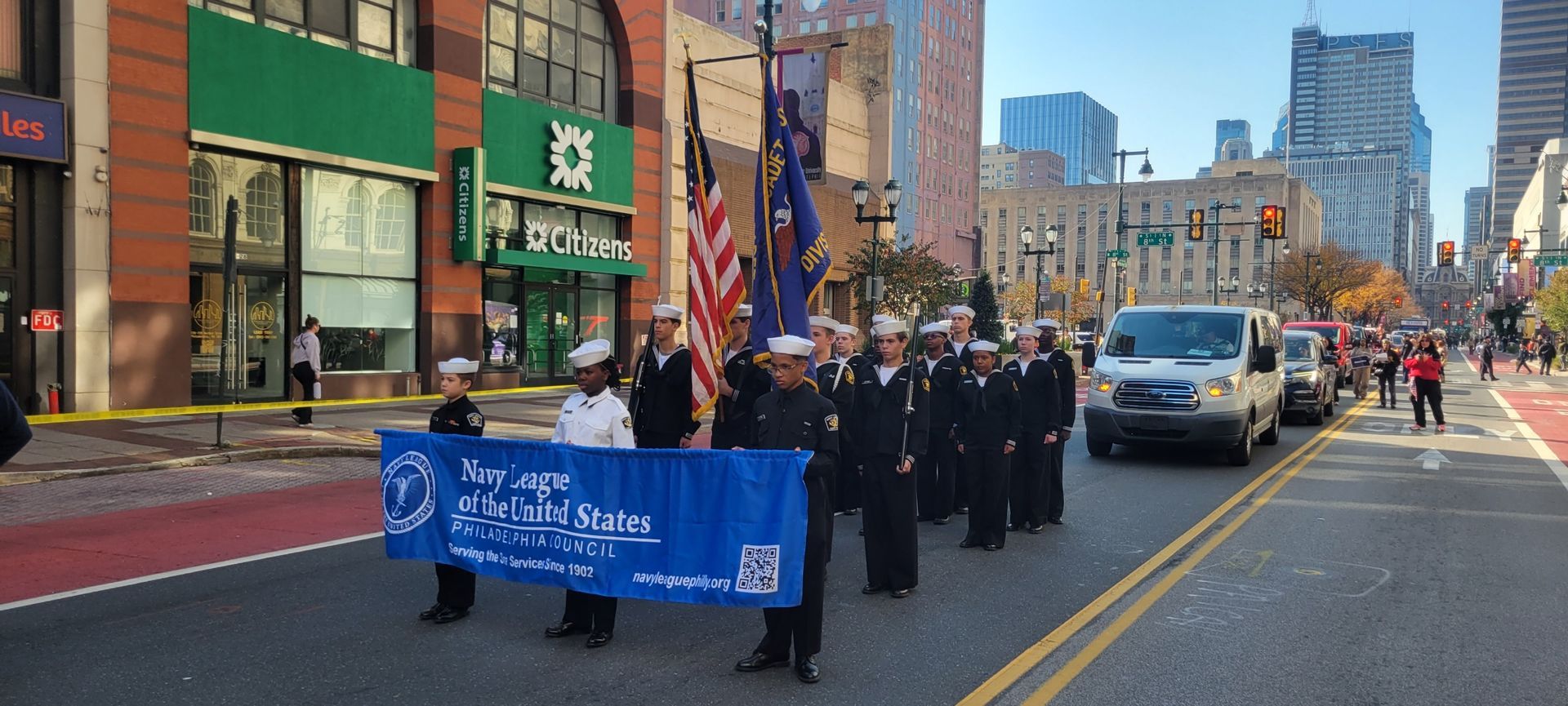 A group of people are holding a blue banner that says navy league of the united states.