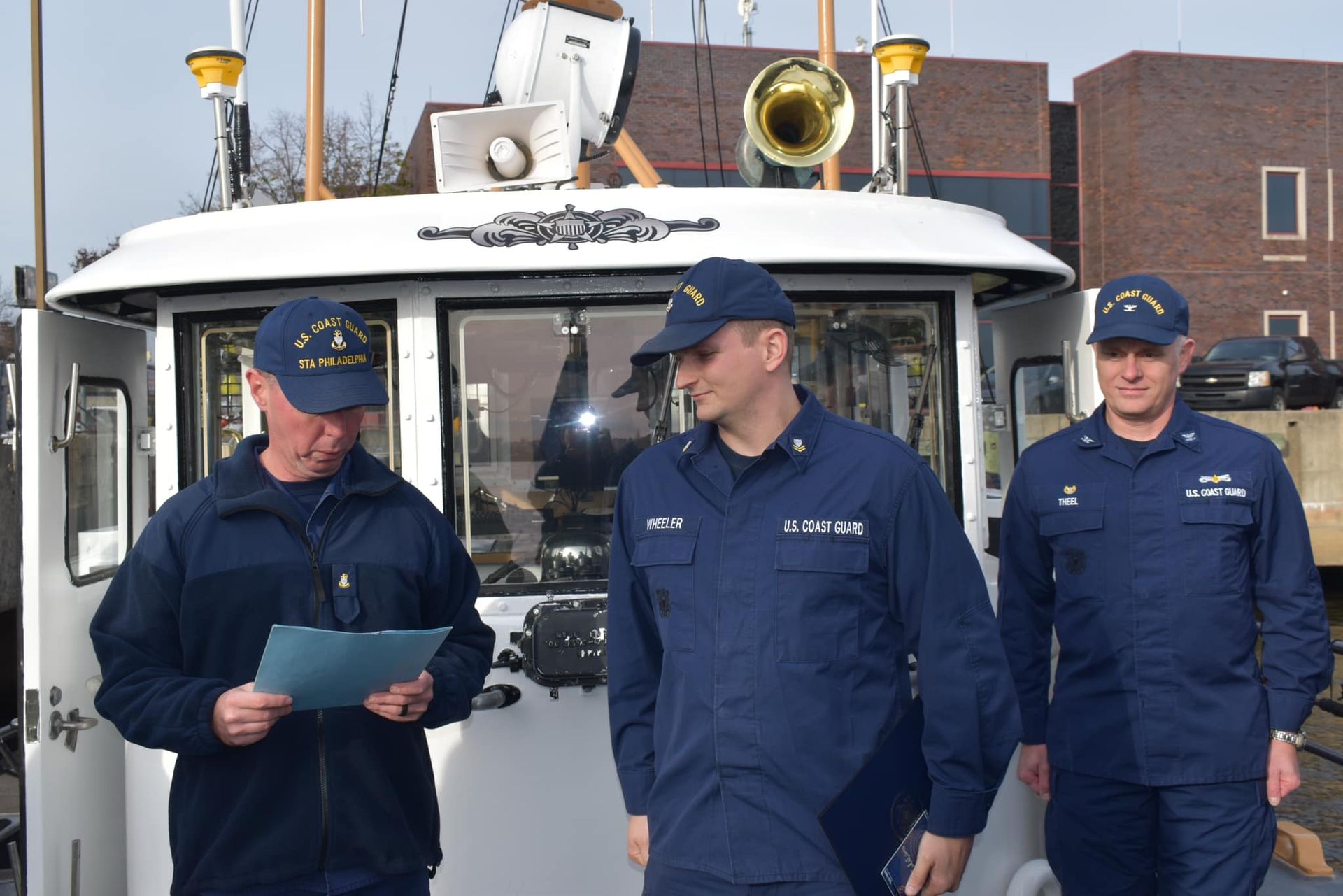 Three men in military uniforms are standing in front of a boat.