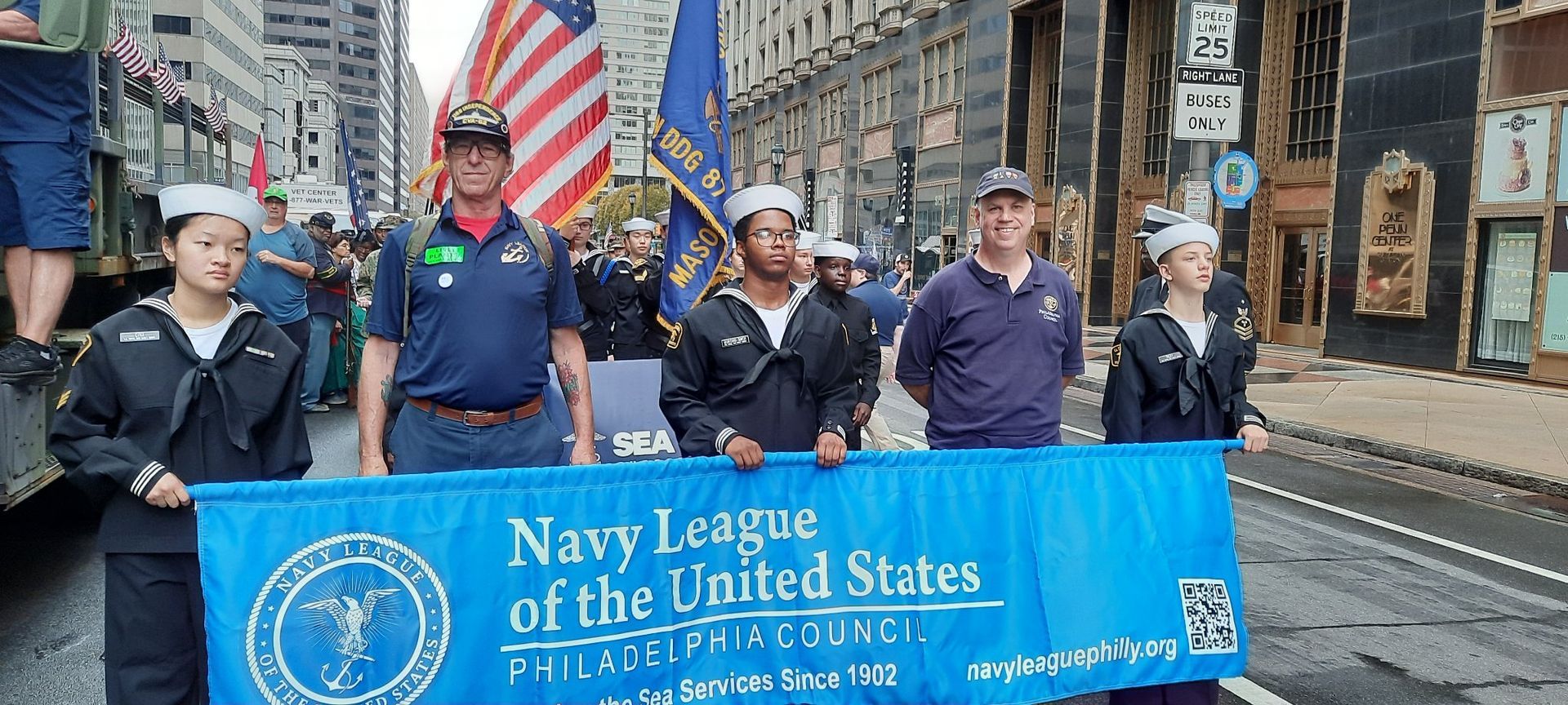 A group of people are holding a banner that says Navy League of The United States.