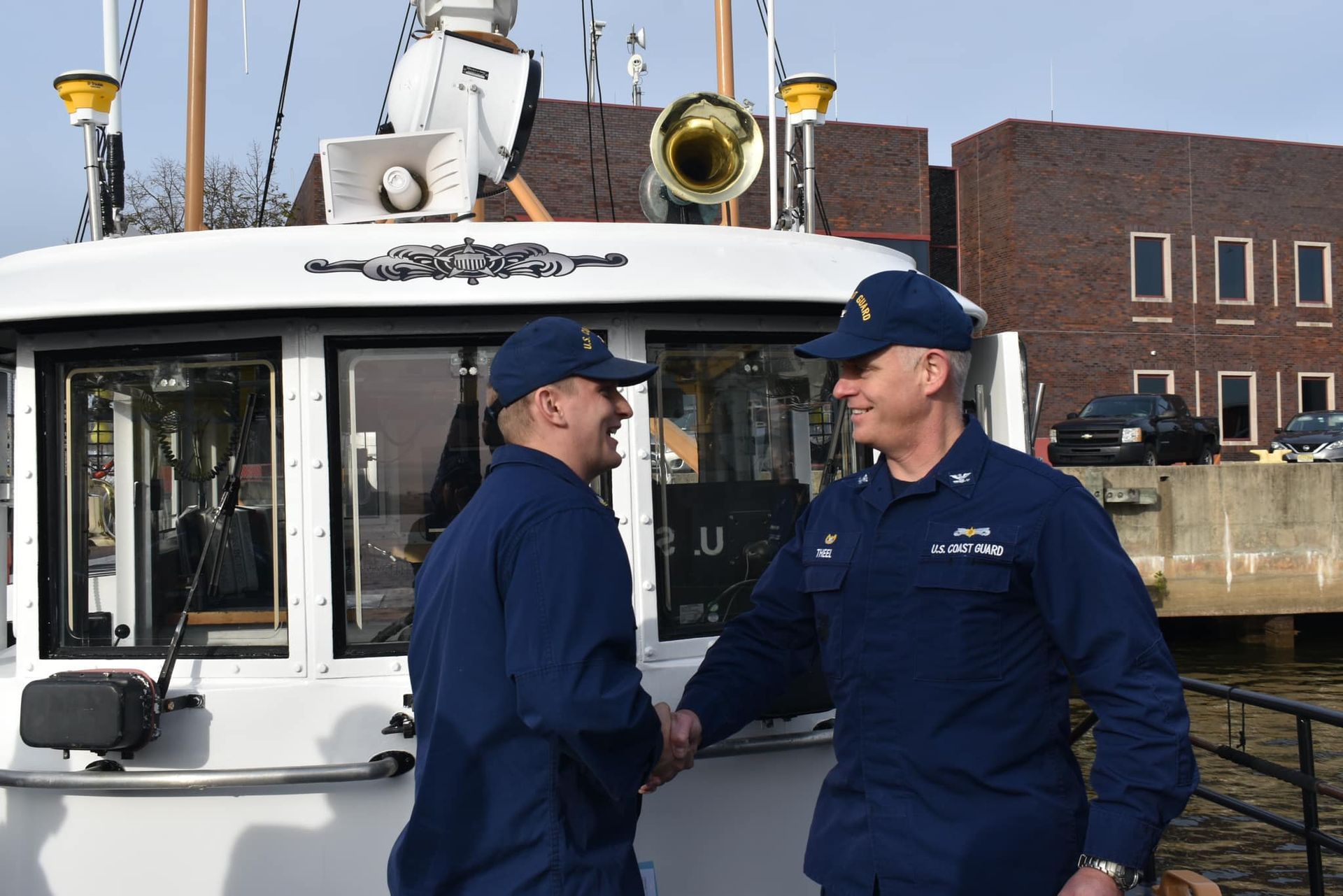 Two men shaking hands in front of a boat