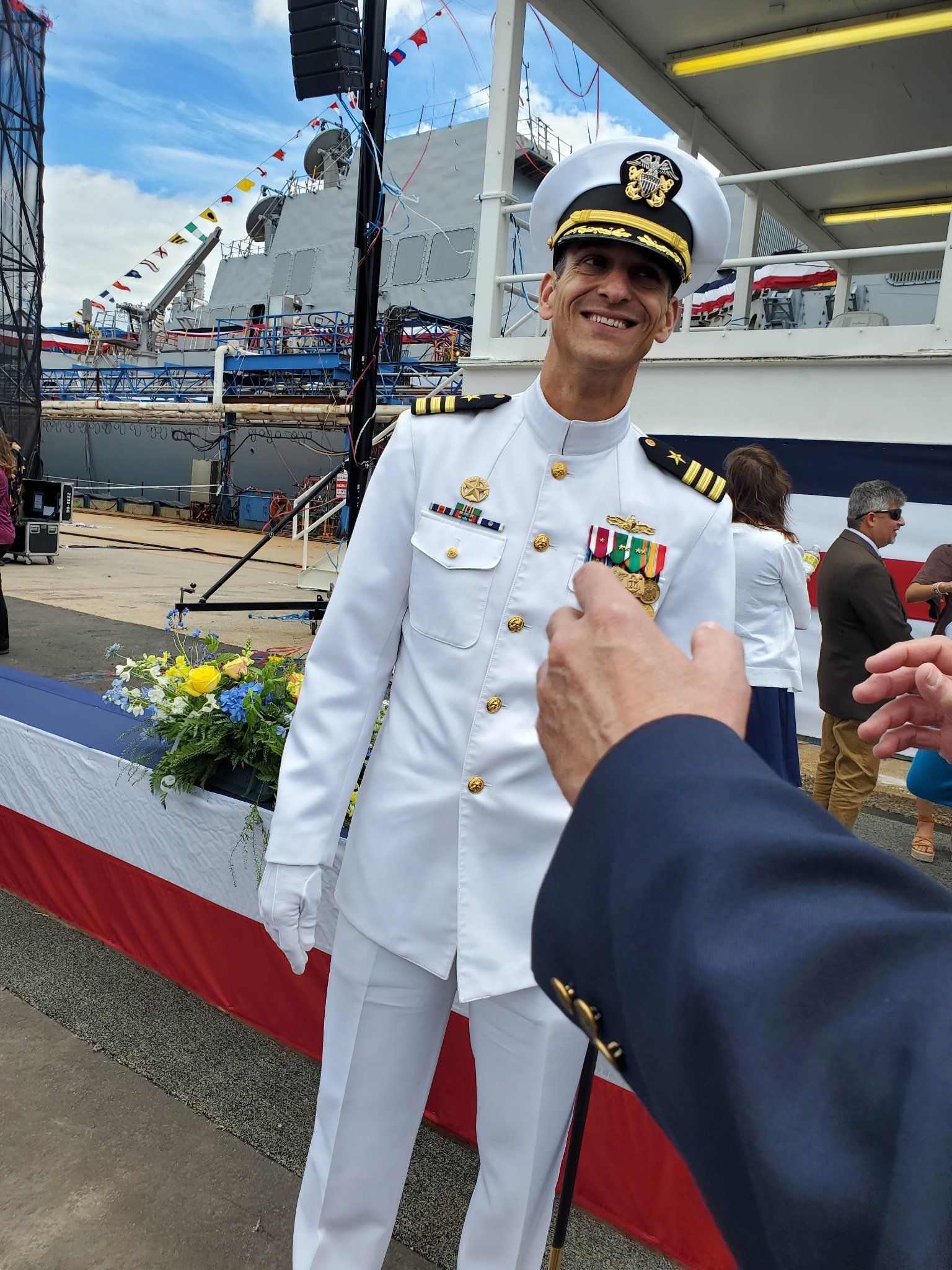 A man in a military uniform is standing in front of a ship