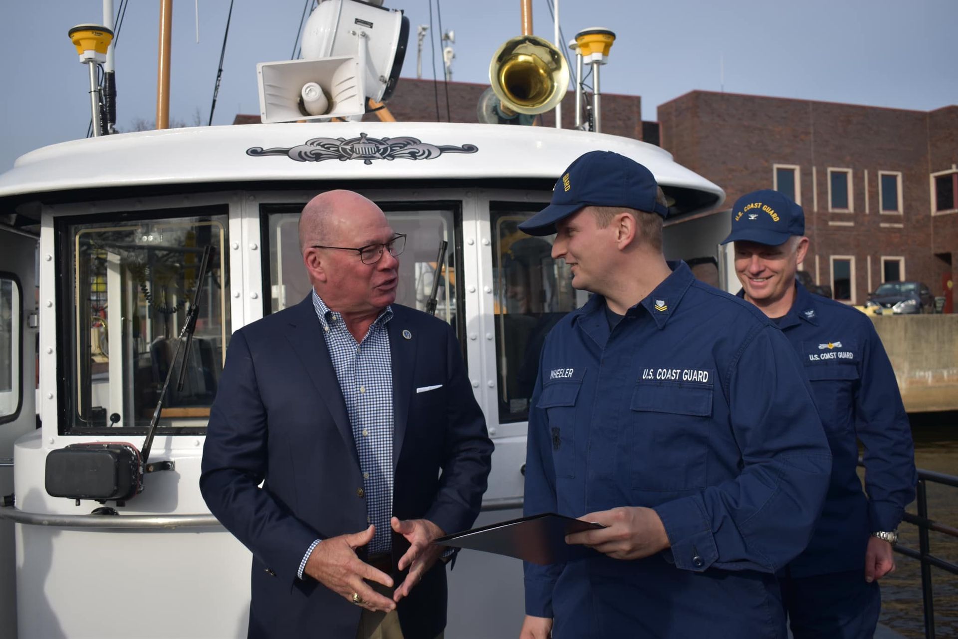 A group of men are standing in front of a boat talking to each other.