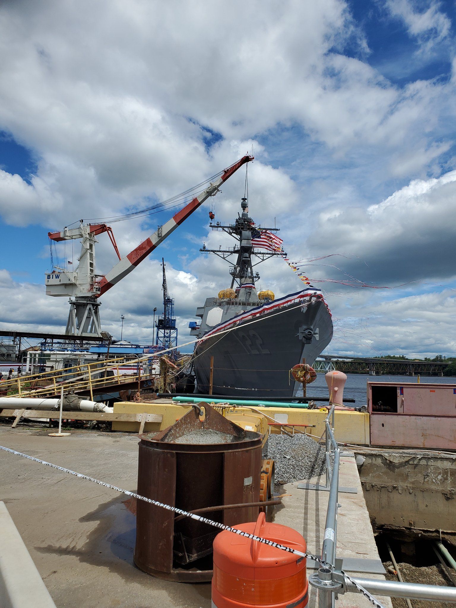 A large ship is docked in a harbor with a crane in the background.