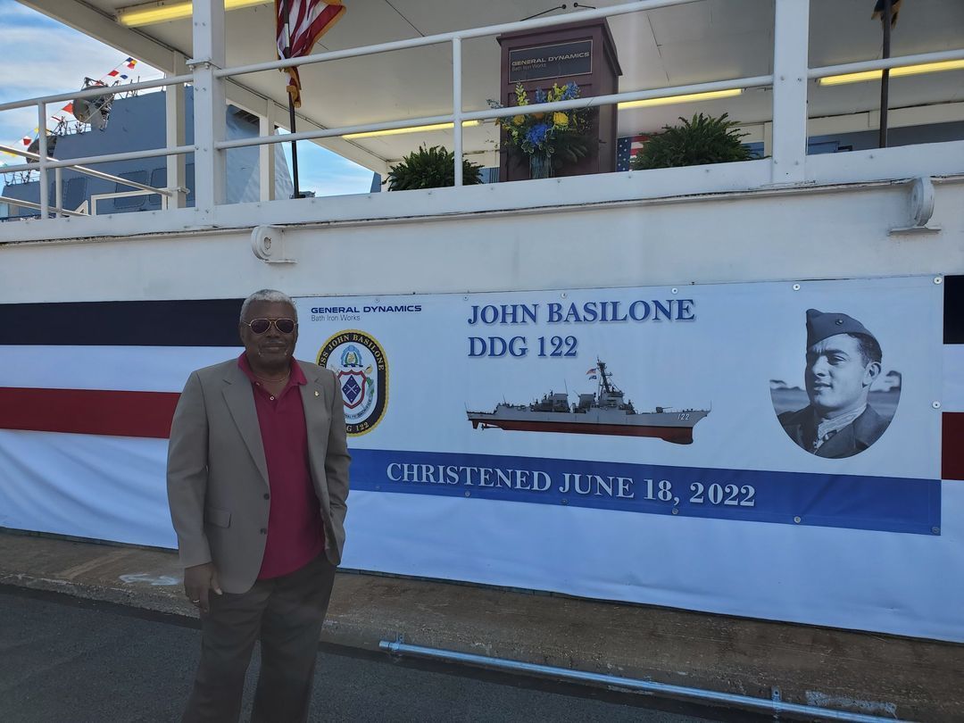 A man stands in front of a banner that says john rashlone