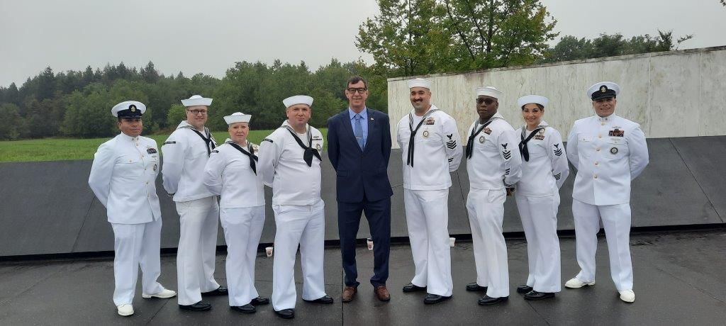 A group of sailors are posing for a picture with a man in a suit.