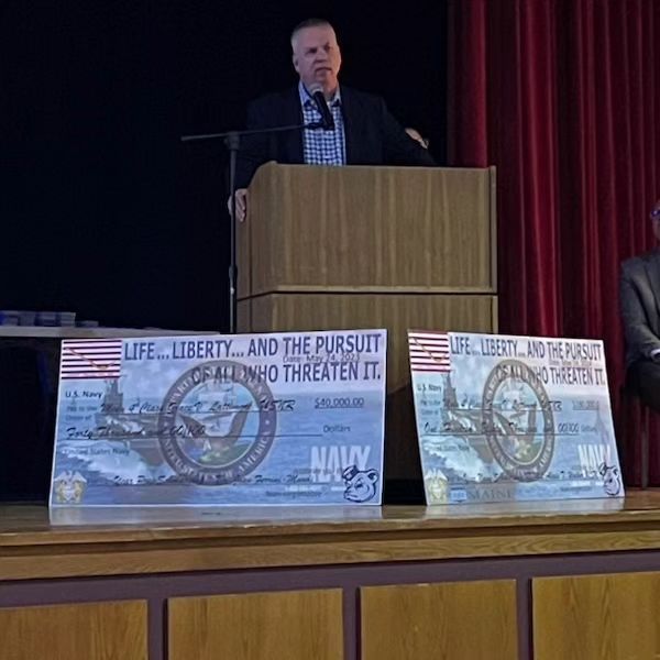 A man stands at a podium with a sign that says life liberty and the pursuit of all who threaten it