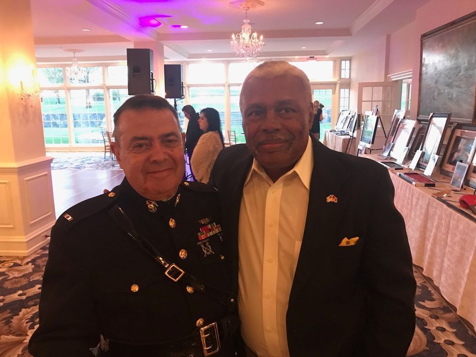 Two men in military uniforms are posing for a picture in a room.