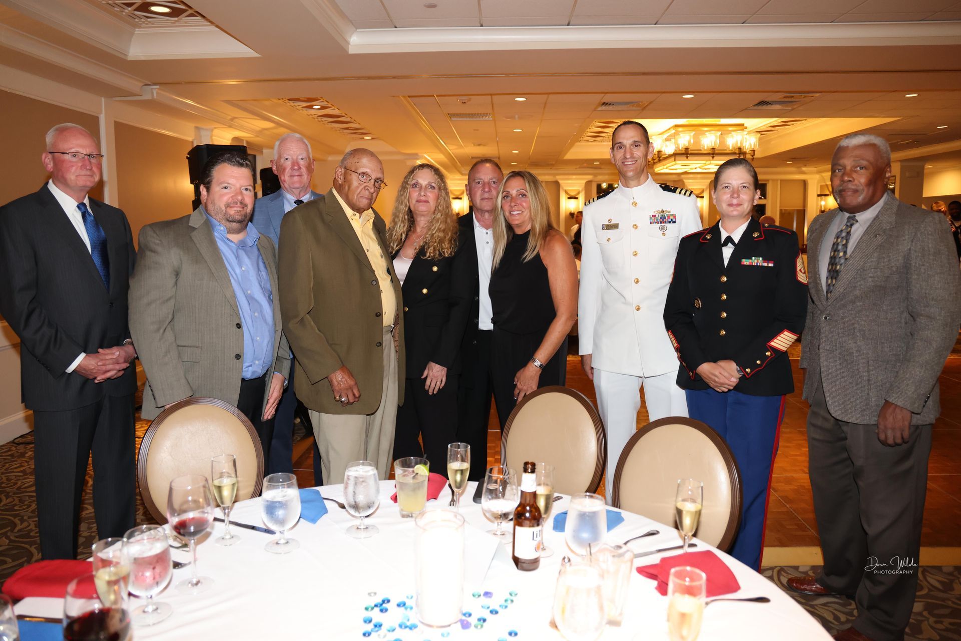 A group of people standing around a table with wine glasses