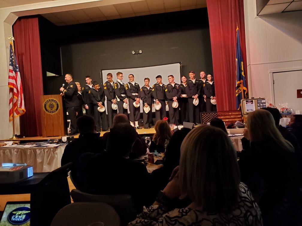 A group of people are standing on a stage in front of a crowd