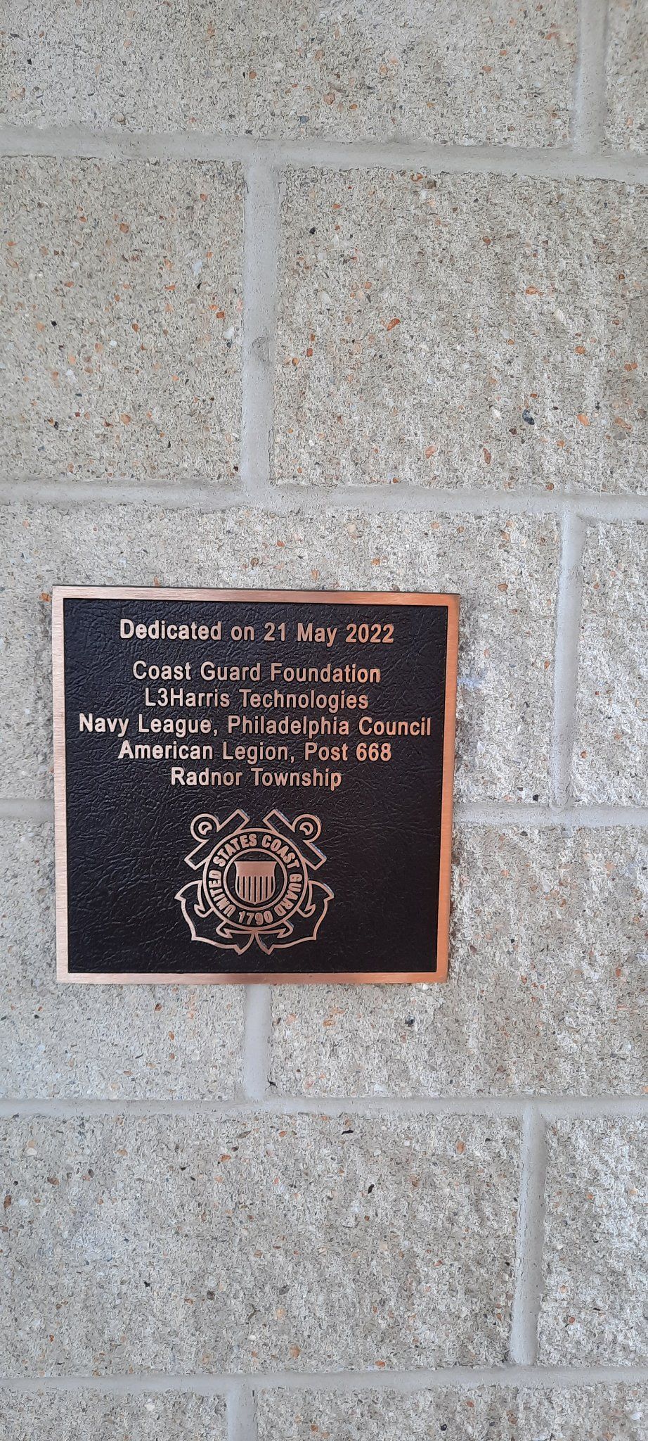 A plaque is sitting on a brick wall.
