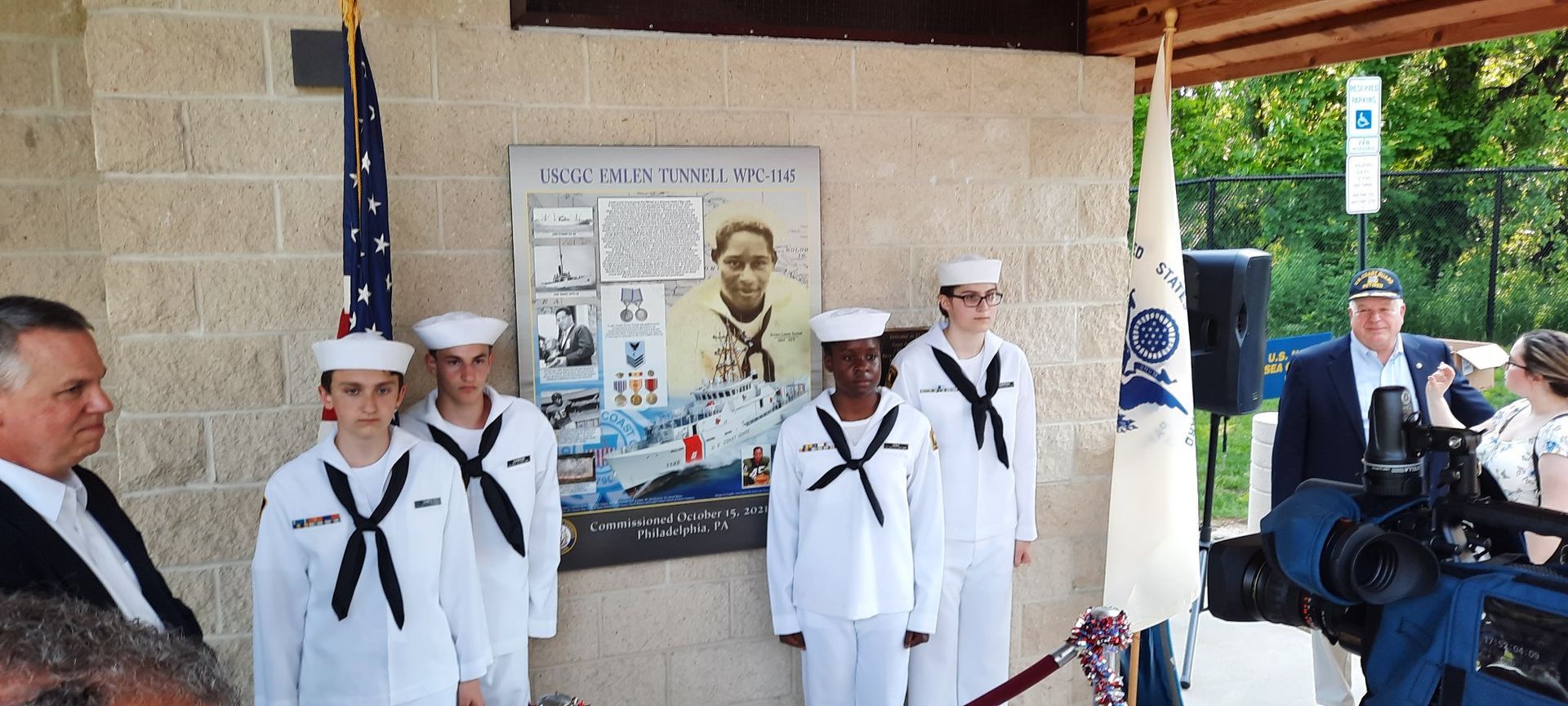 A group of sailors are standing in front of a wall with a picture of a man on it.