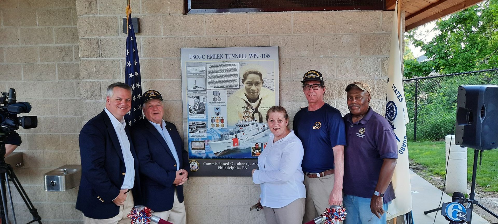 A group of people standing in front of a wall with a picture of a man on it