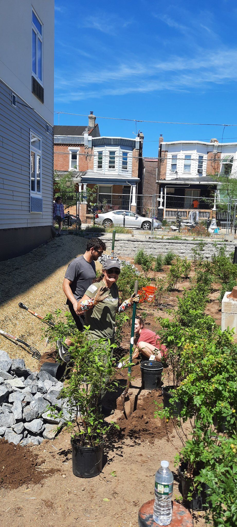 A group of people are working in a garden in front of a building.