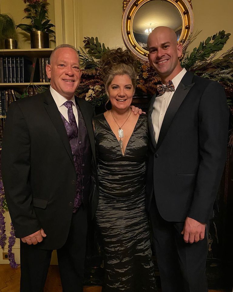 Two men and a woman are posing for a picture in a living room.