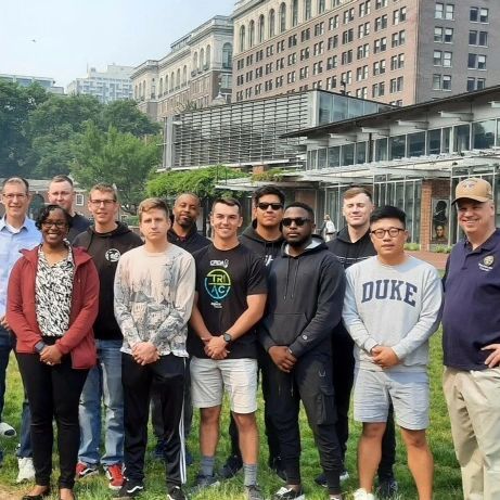 A group of people posing for a picture with one man wearing a duke sweatshirt