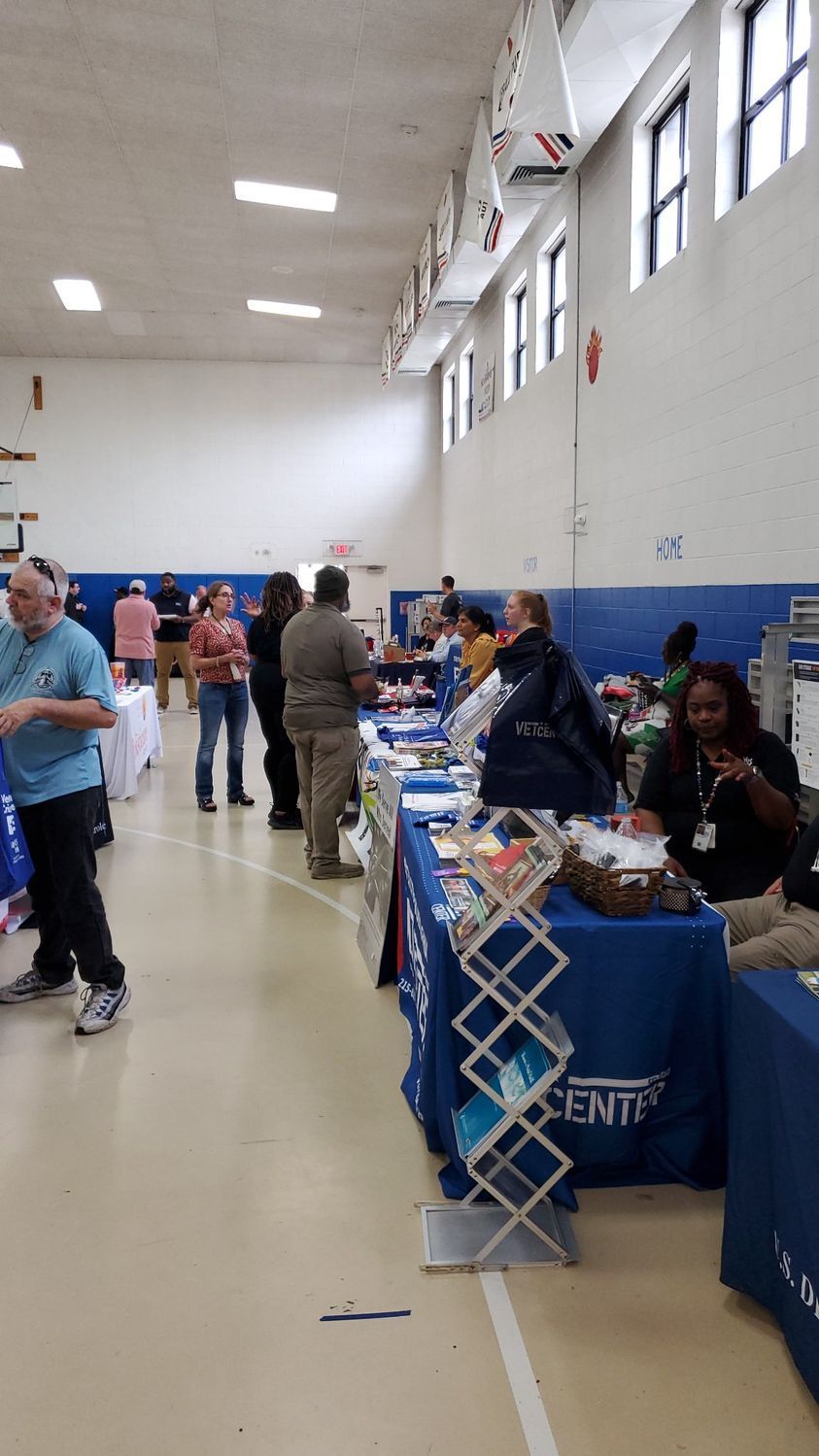 A group of people are standing around tables in a gym