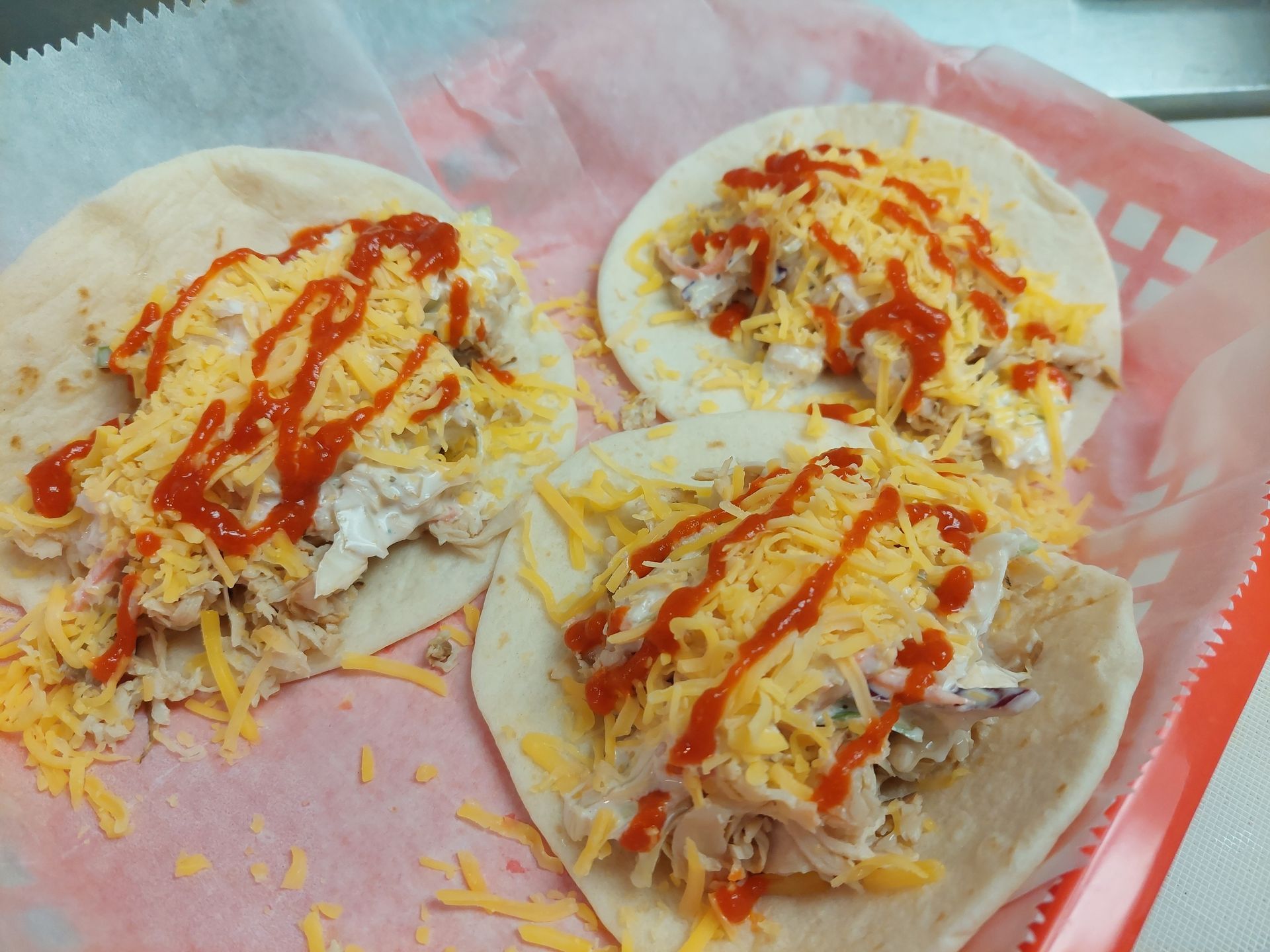 Three tacos with cheese and ketchup on a tray