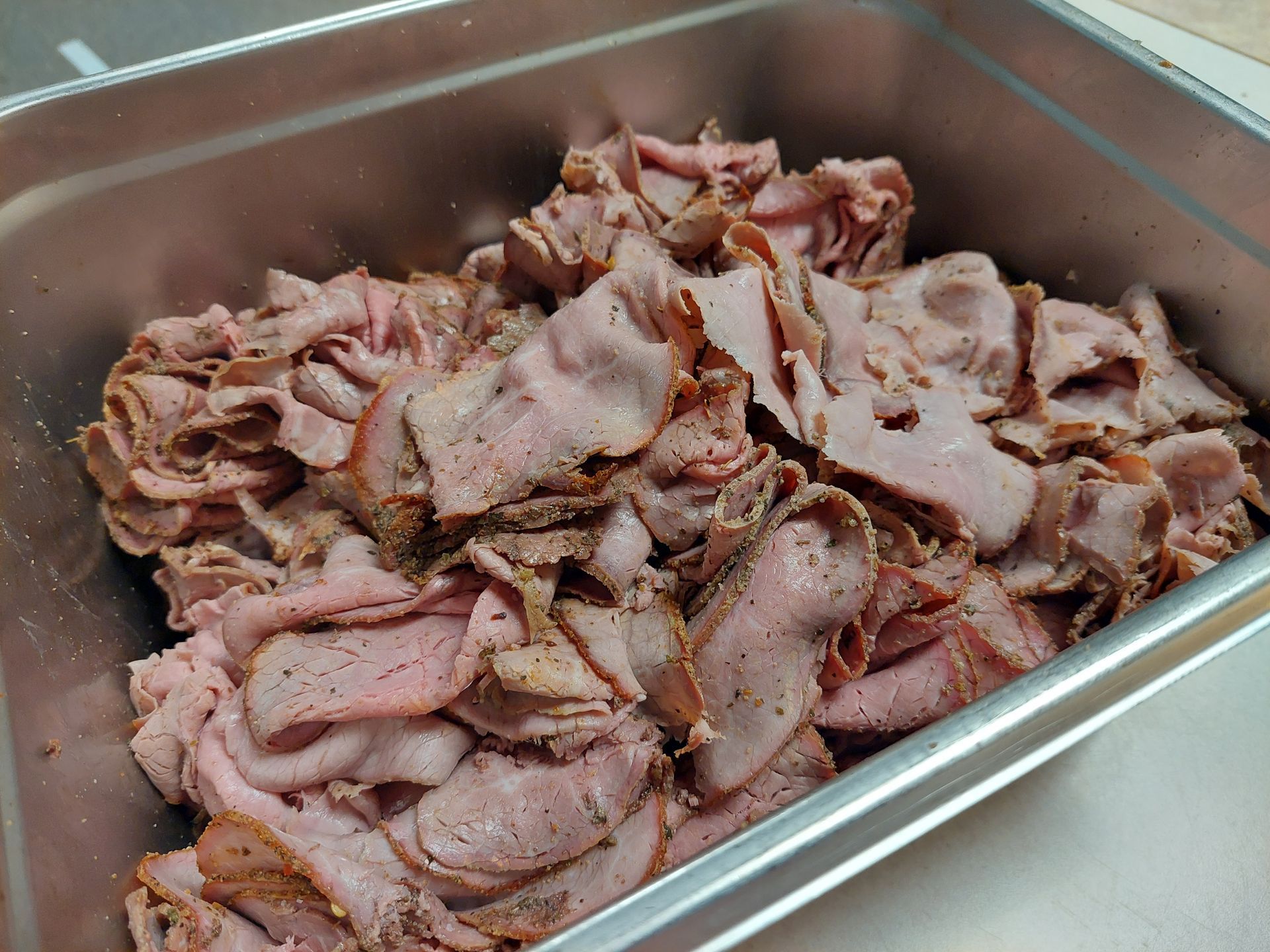 A tray of sliced roast beef is sitting on a table.