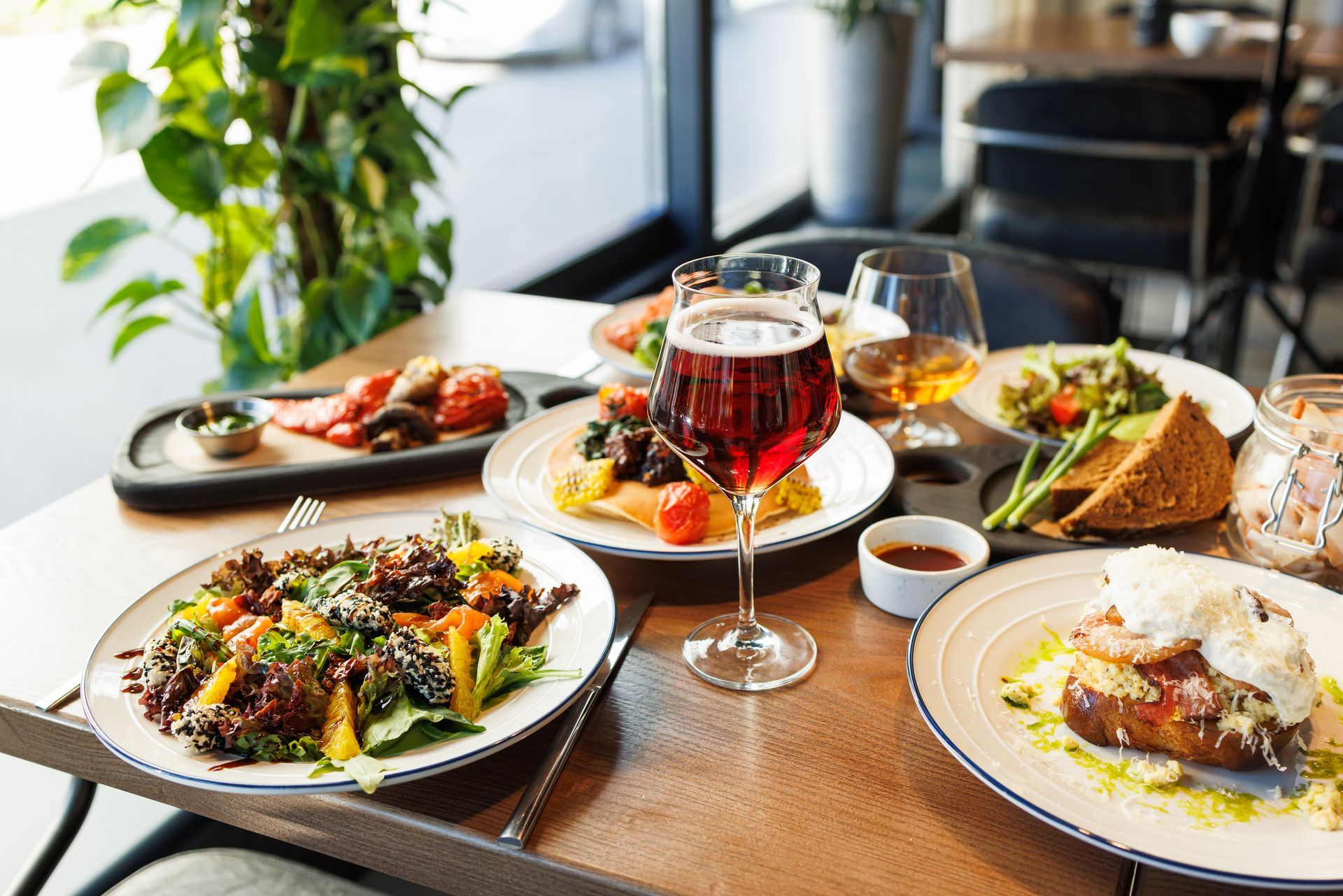 A table topped with plates of food and a glass of wine.