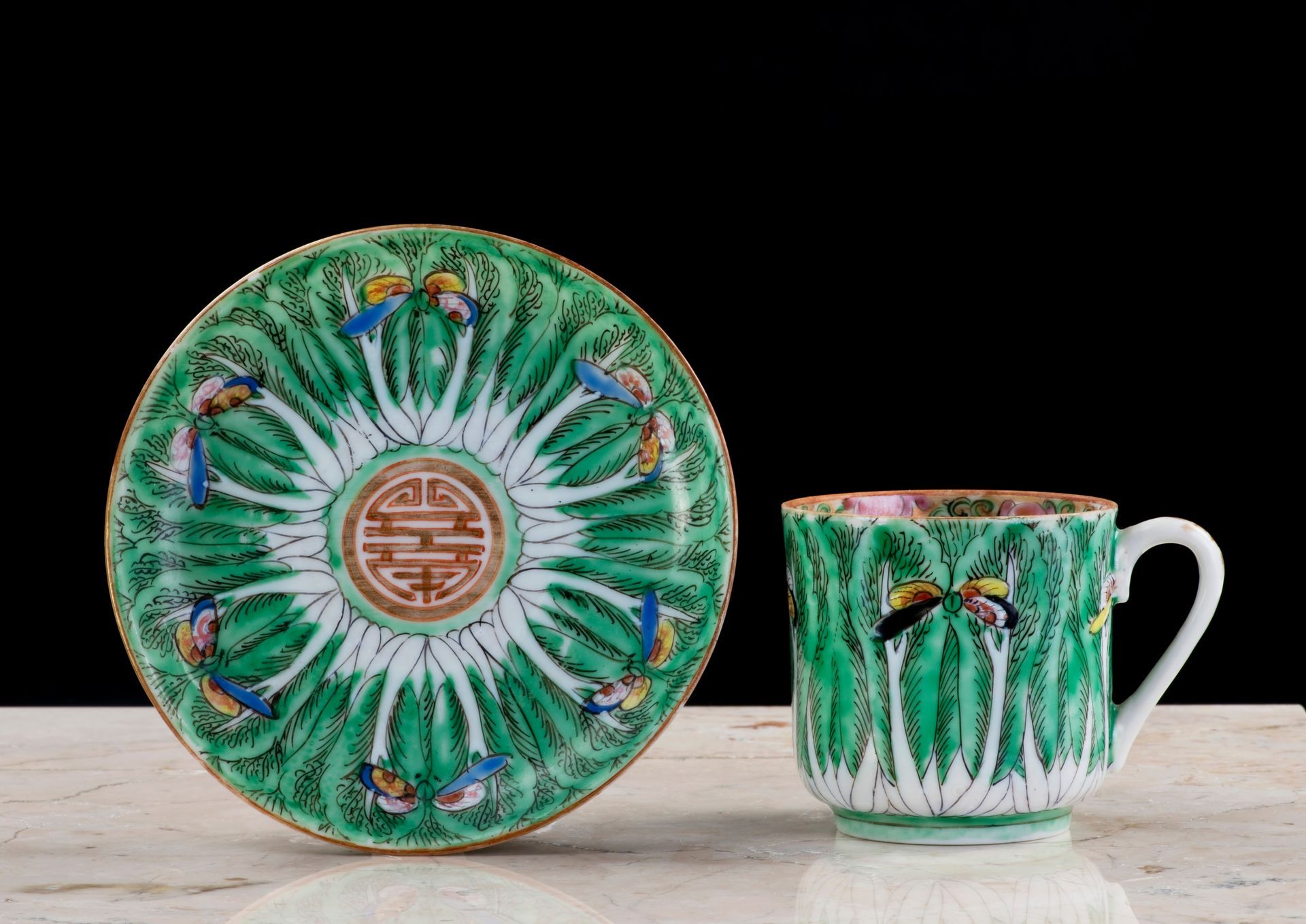 A green cup and saucer are sitting on a table.