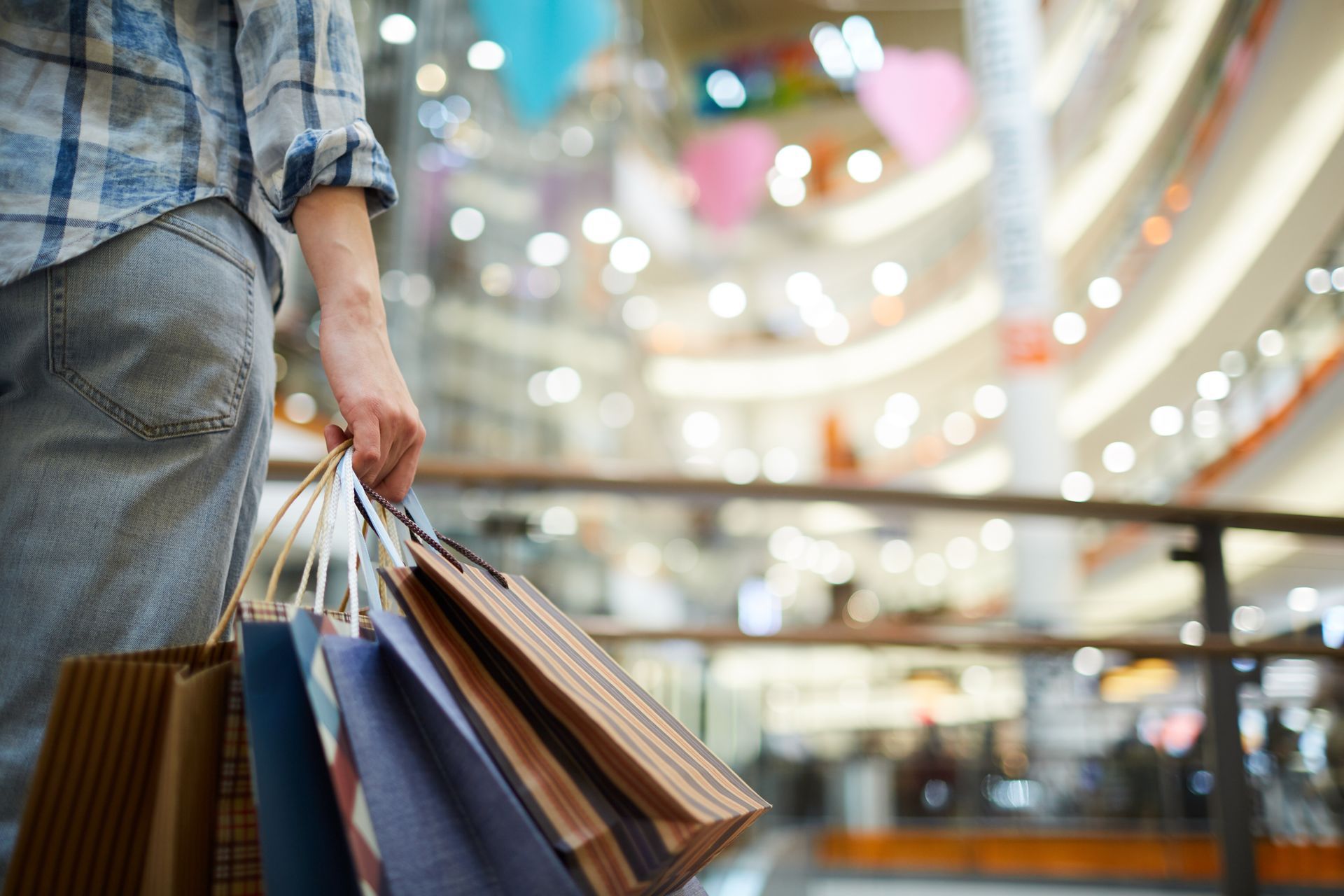 A person is holding shopping bags in a mall.