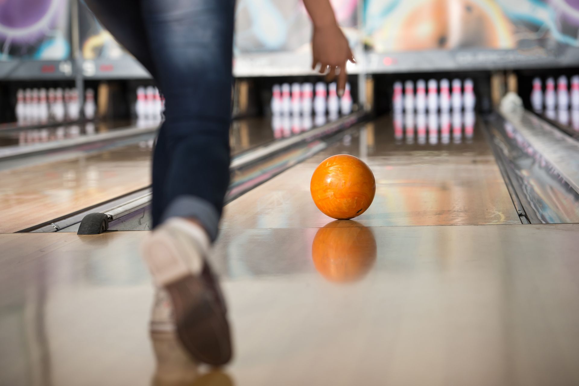 A woman is throwing a bowling ball down a bowling alley.