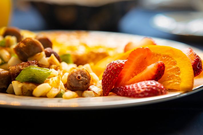 A plate of food with strawberries and oranges on a table.