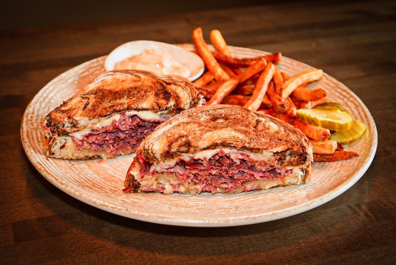A sandwich and french fries on a plate on a table.
