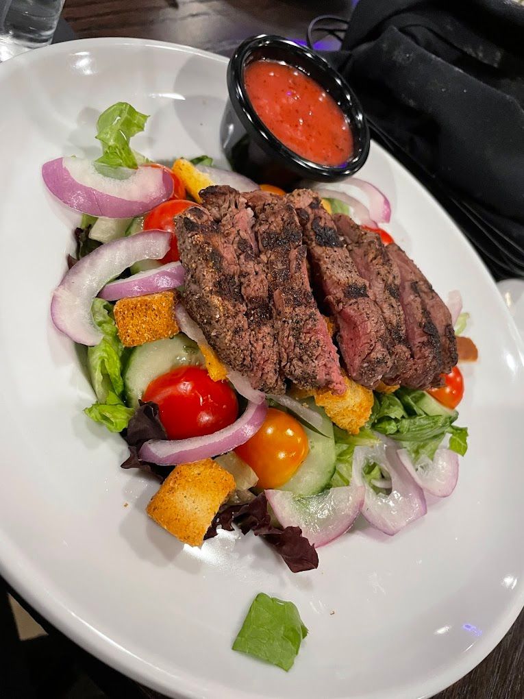 A white plate topped with a salad and a steak.