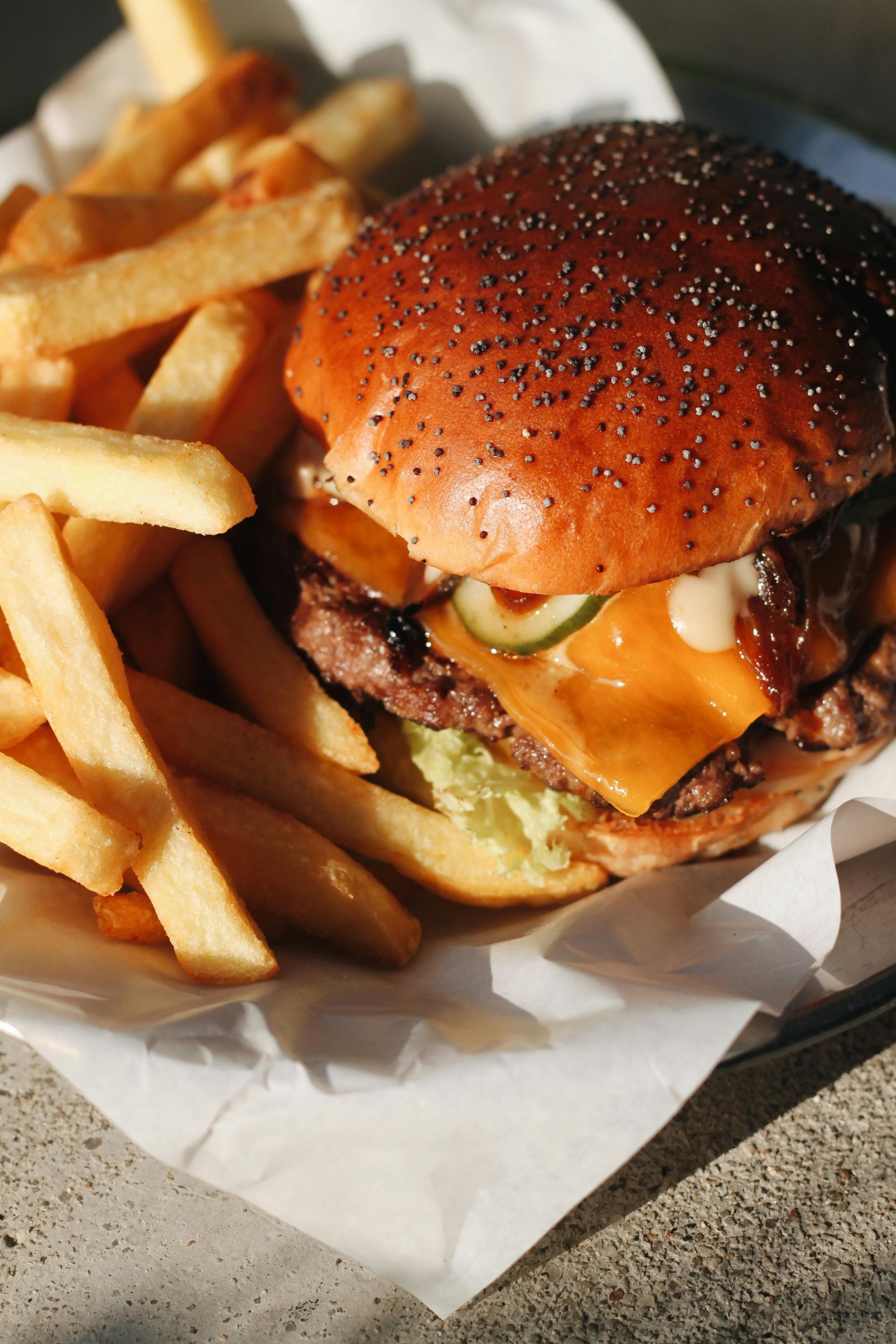 A close up of a hamburger and french fries on a table.