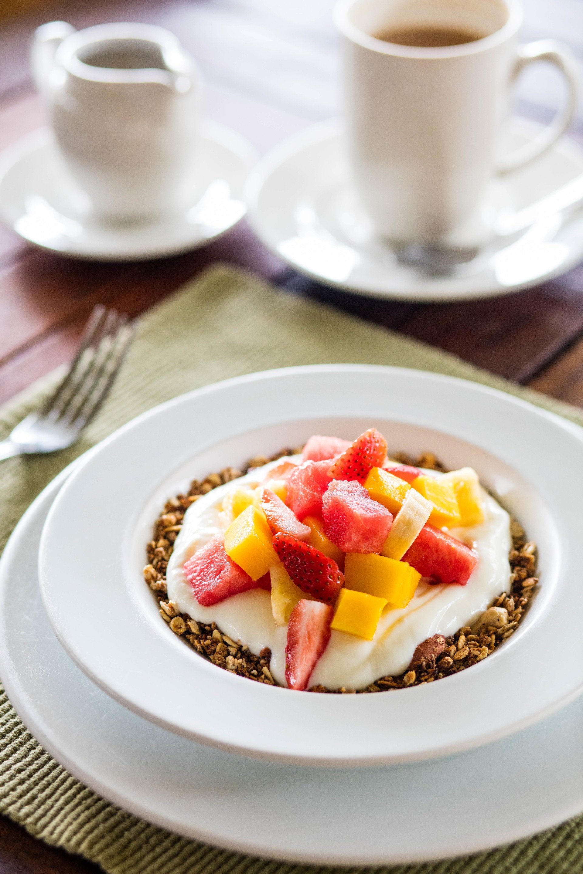 A bowl of granola with yogurt and fruit on a table