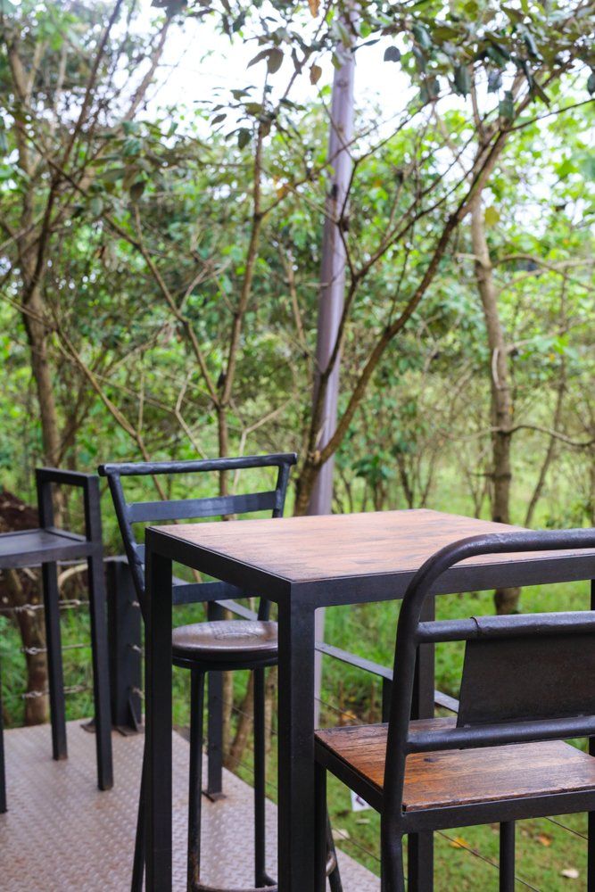 A wooden table and chairs are sitting on a deck in the woods.