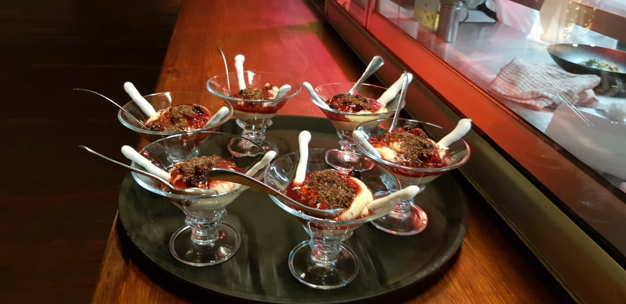 A tray of desserts with spoons in them on a table.