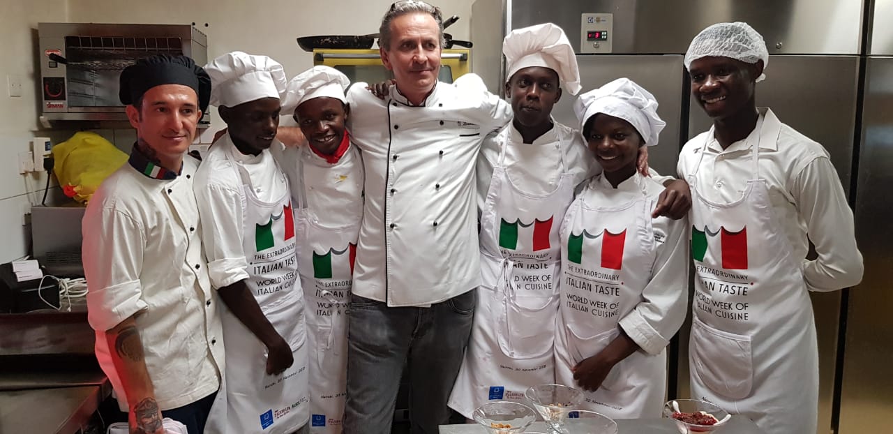 A group of chefs are posing for a picture in a kitchen.