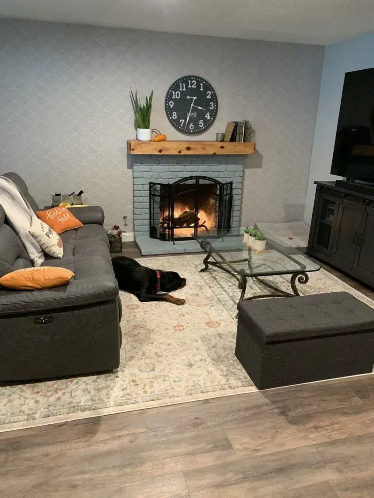Cozy living room with a fireplace, dark couch, dog, and coffee table.