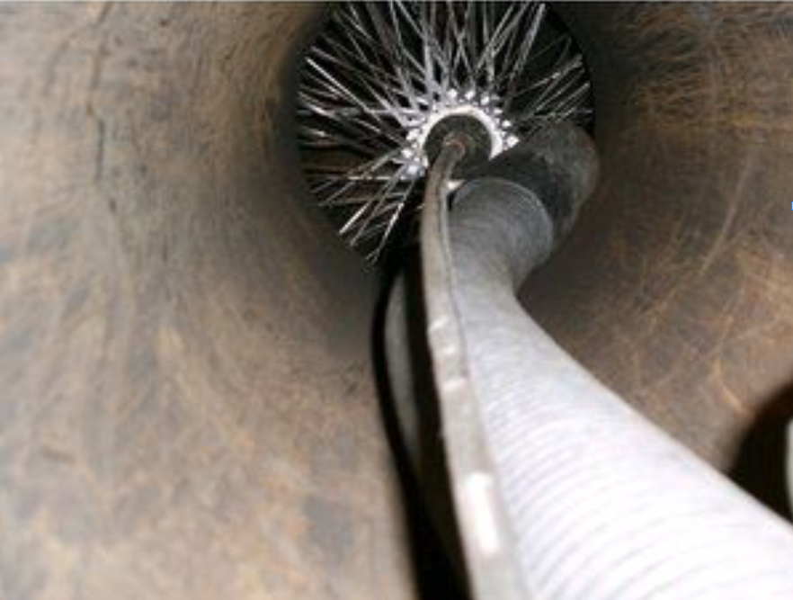 Person sits atop a brick chimney, pulling a wire; cloudy sky, roof below.