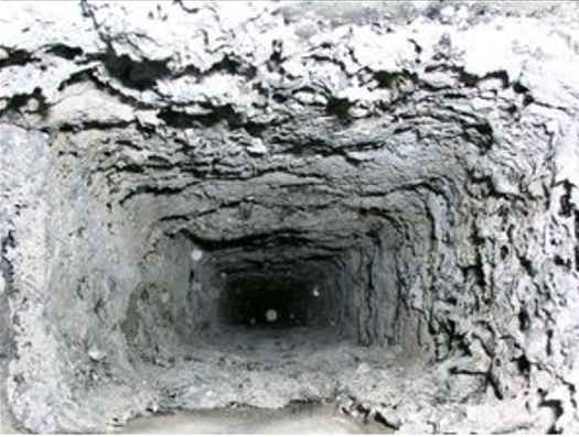 A person on a red tile roof, near a chimney, against a cloudy sky. They are wearing black and holding tools.