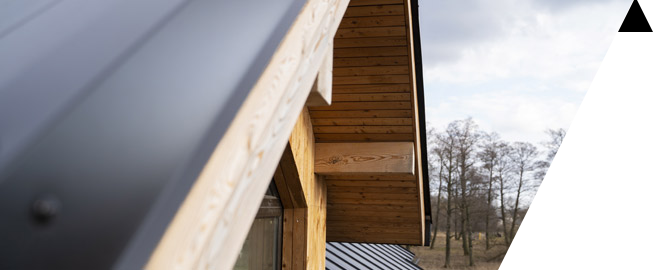 A close up of a wooden house with a black roof.