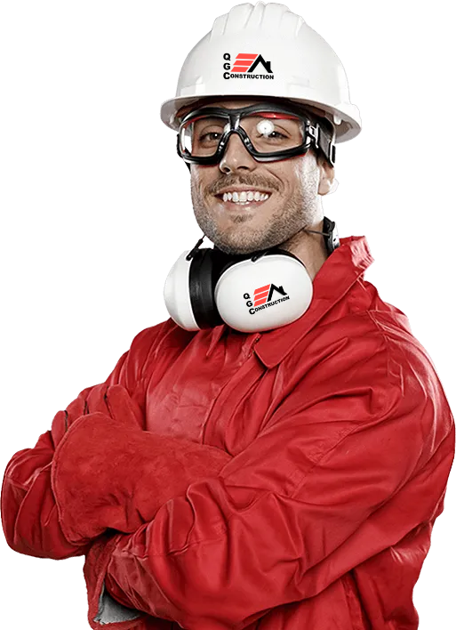 A man wearing a hard hat , headphones , goggles and a red jacket is standing with his arms crossed.