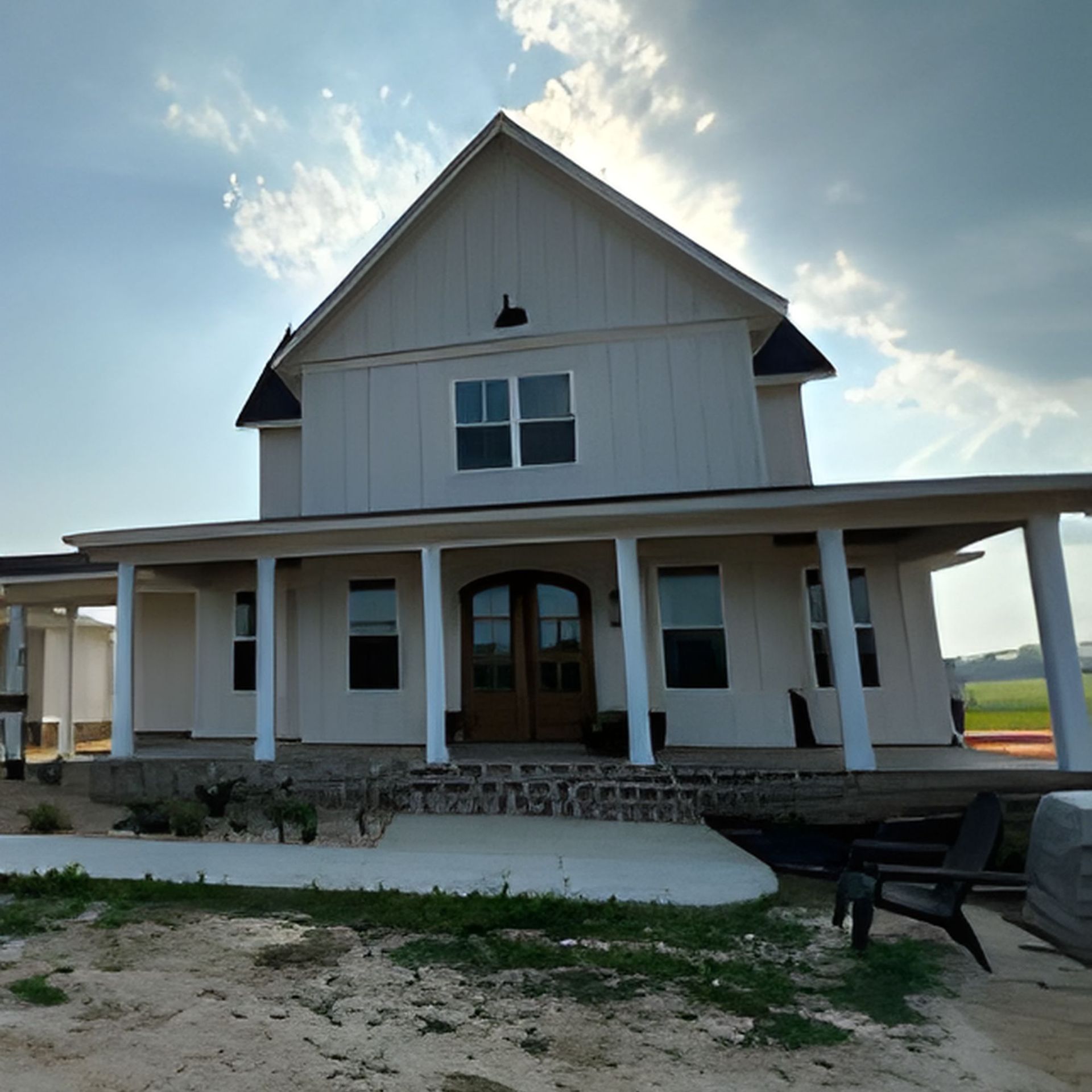 White two-story farmhouse with a wrap-around porch under a bright sky.