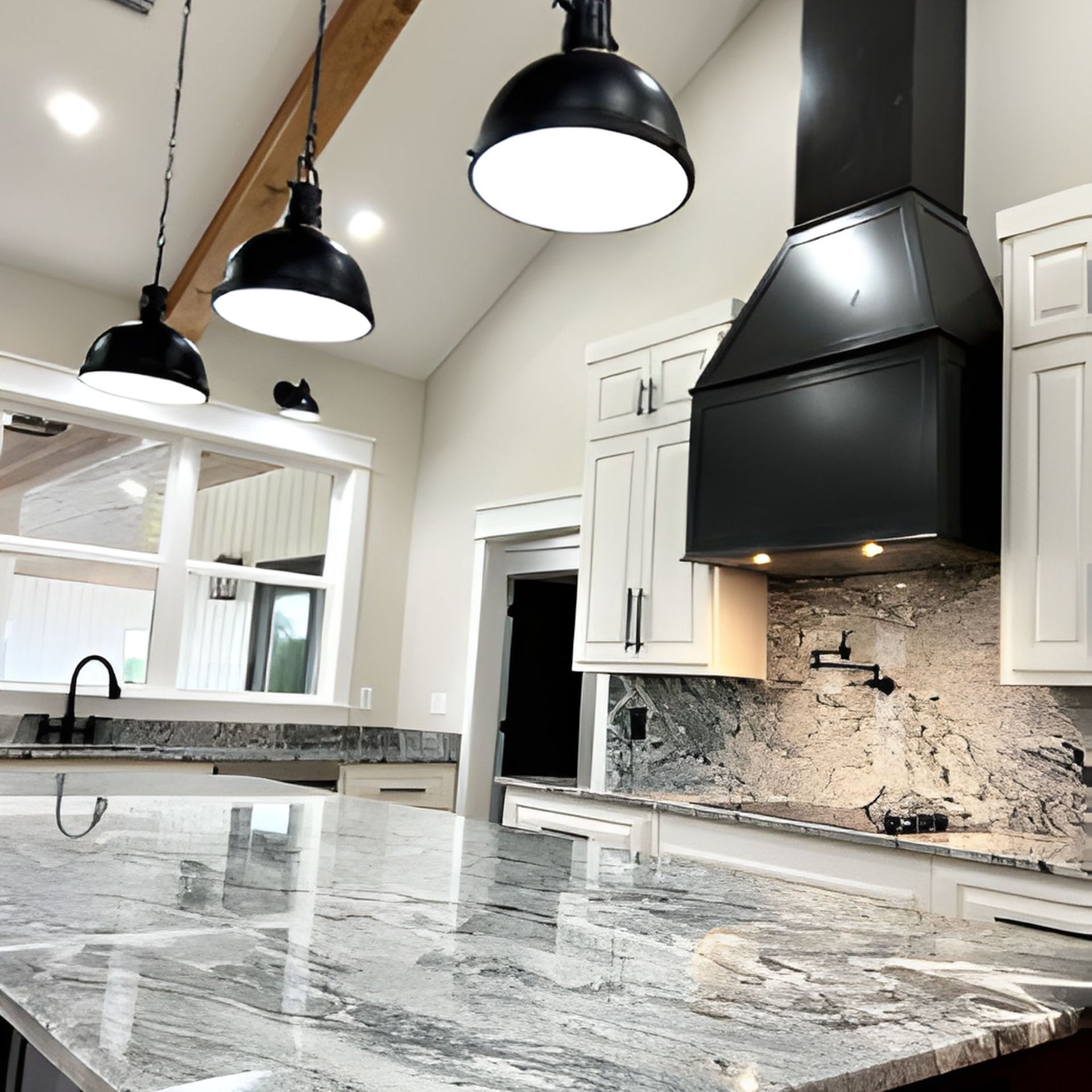 Modern kitchen with granite countertops, black hood, white cabinets, and pendant lights.