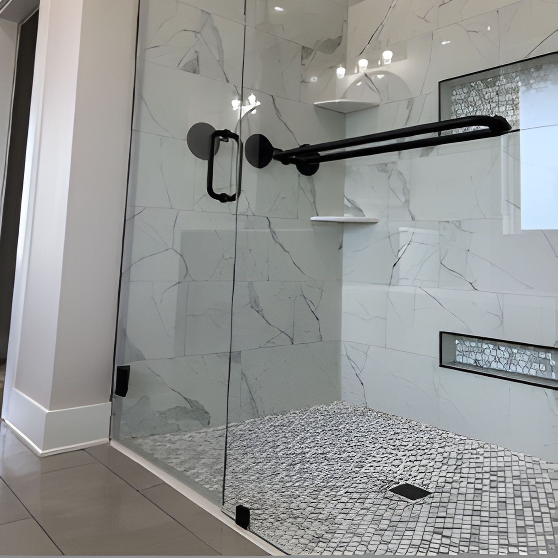 A modern shower with marble-look tiles, glass door, black hardware, and mosaic tile floor.