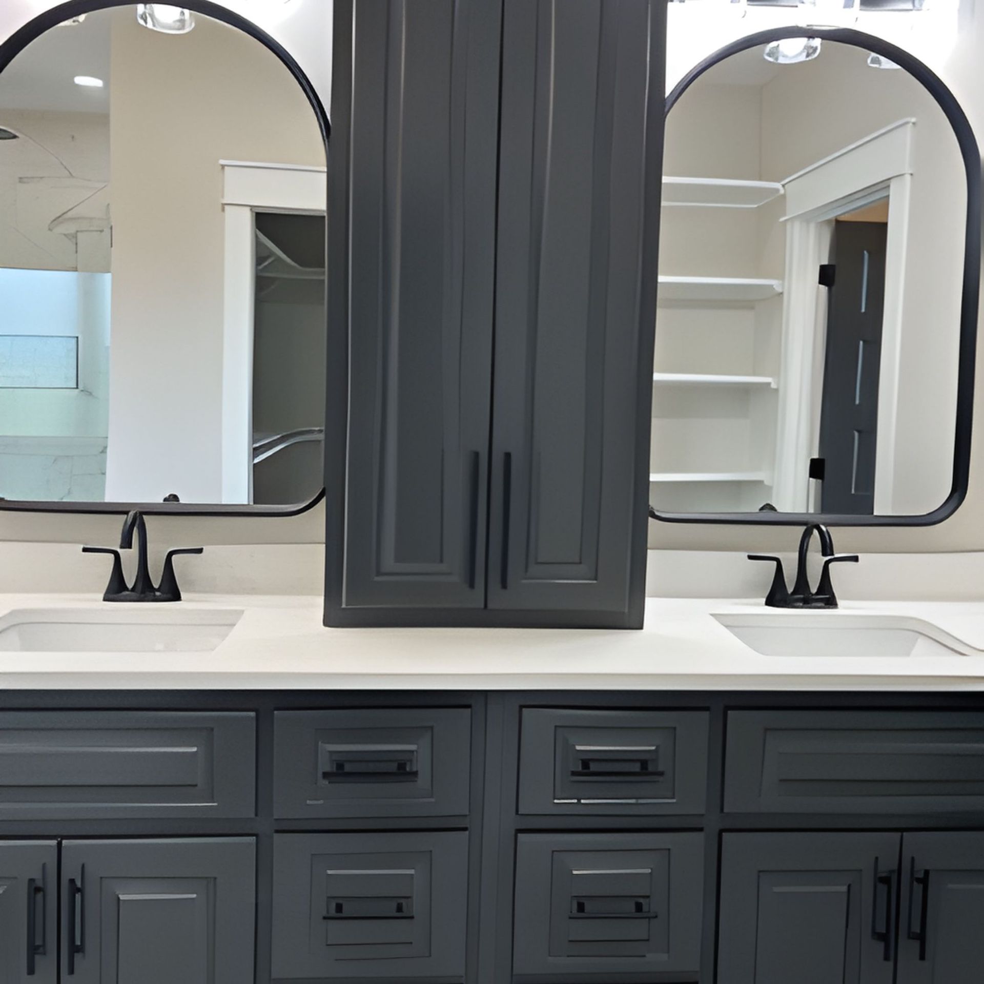 Bathroom vanity with dark gray cabinets, white countertop, black fixtures, and arched mirrors.