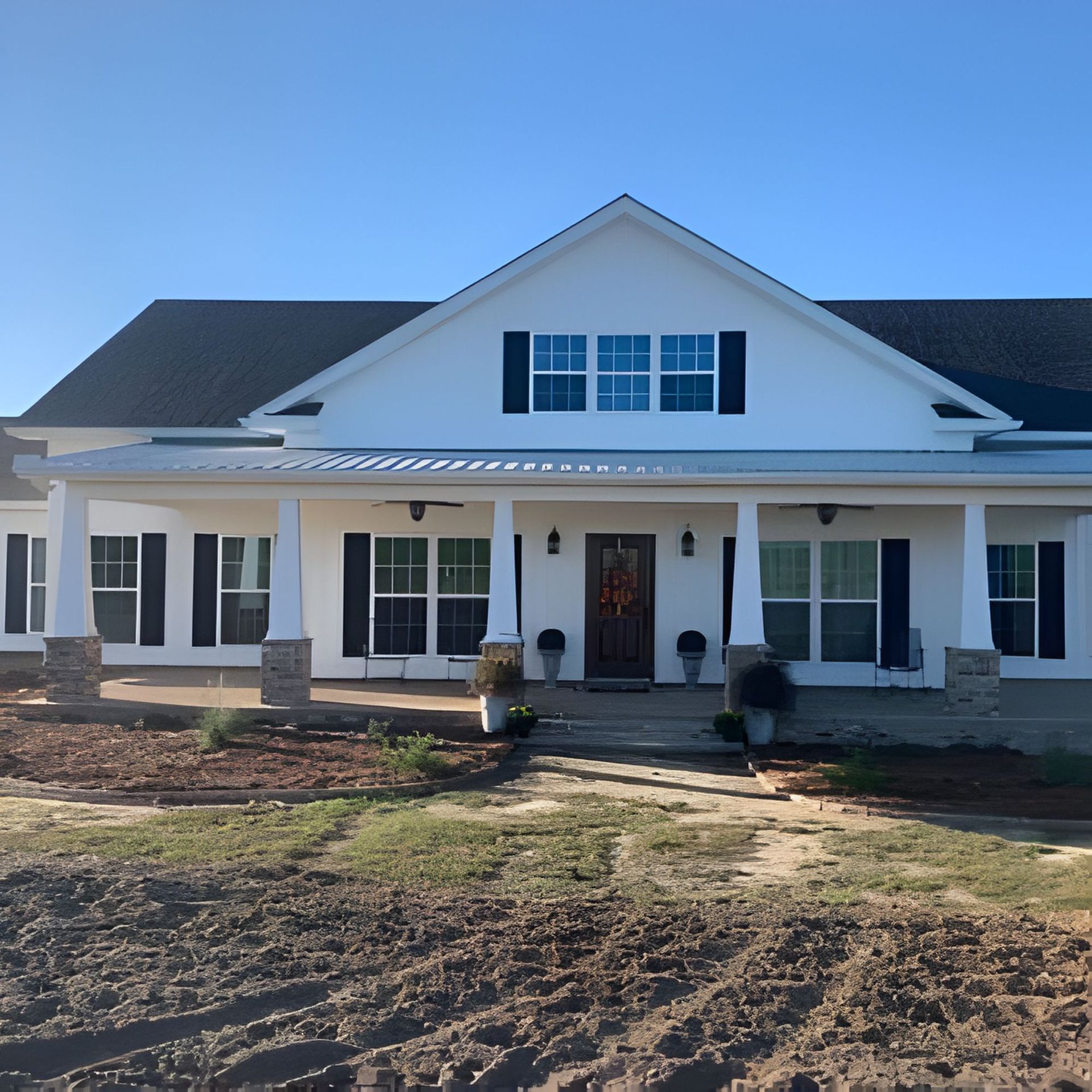 White farmhouse with black shutters and a covered porch on a sunny day.